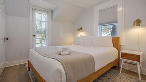 Une chambre à coucher avec un lit, une table de chevet, une lampe et une fenêtre avec des stores.