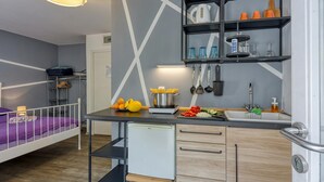 Una habitación de hotel compacta con kitchenette, una cama, un refrigerador pequeño y un comedor.