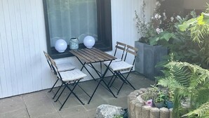 A patio with a table and chairs, a window with a view, and potted plants. - Quiet, fully equipped guest apartment (Mettmann)