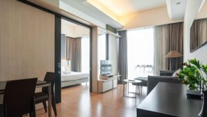 Una habitación de hotel moderna con comedor, sala de estar y balcón con vistas.