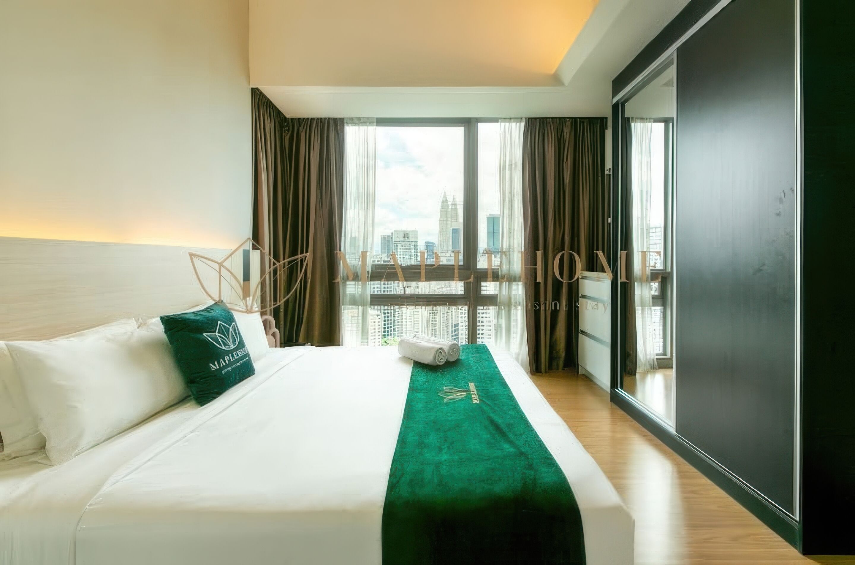 Een hotelkamer met een bed, een groene plaid en uitzicht op de stad door grote ramen.