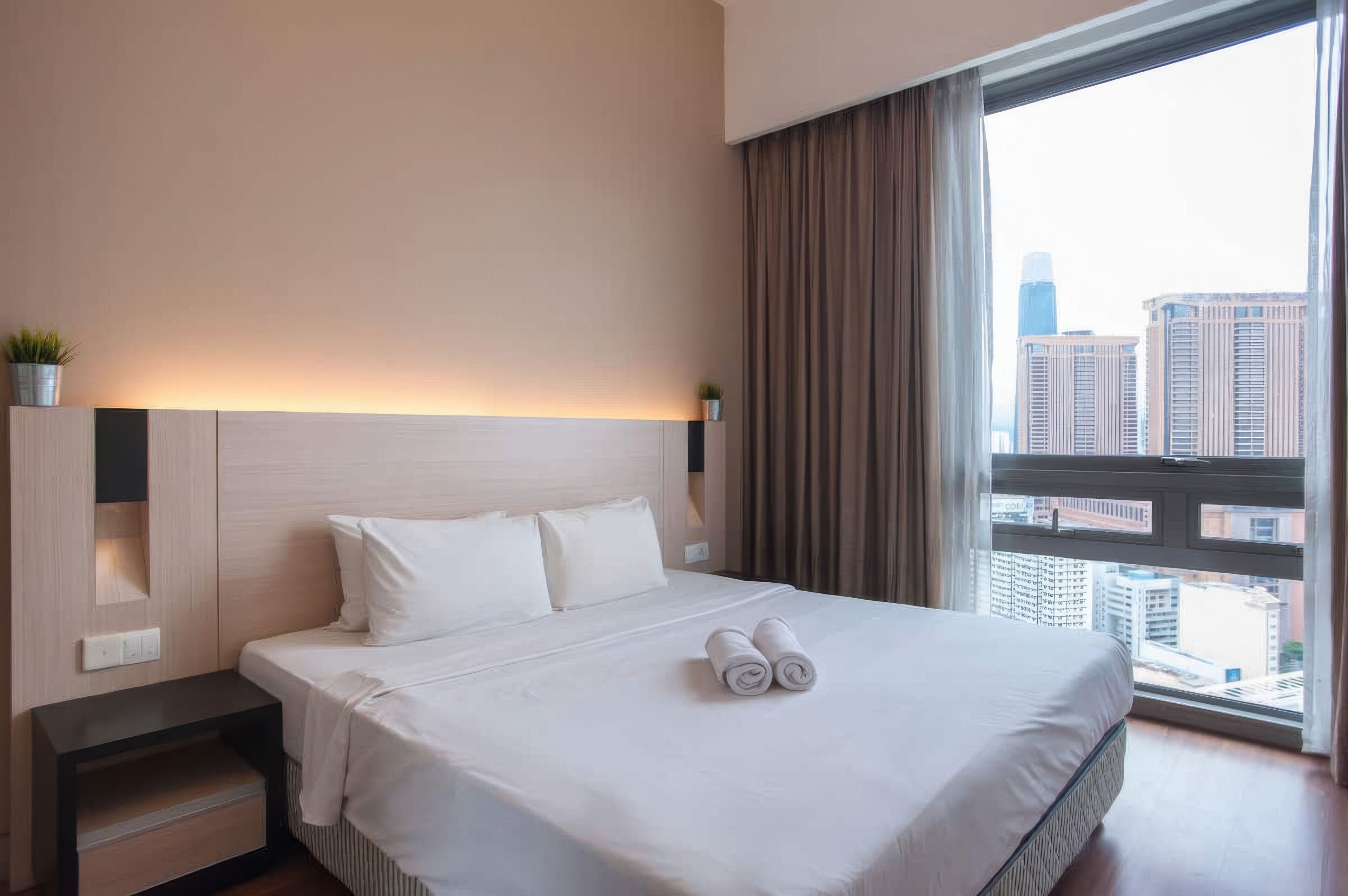Une chambre d’hôtel avec un grand lit, une table de chevet, une fenêtre avec des rideaux et une vue sur la ville.