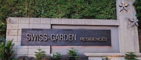 A sign for Swiss-Garden Residences with a stone wall and decorative elements.