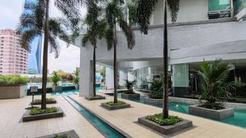 A modern indoor pool area with multiple pools, surrounded by palm trees and planters.