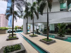 Un espace piscine intérieure moderne, doté de plusieurs bassins, entouré de palmiers et de jardinières.