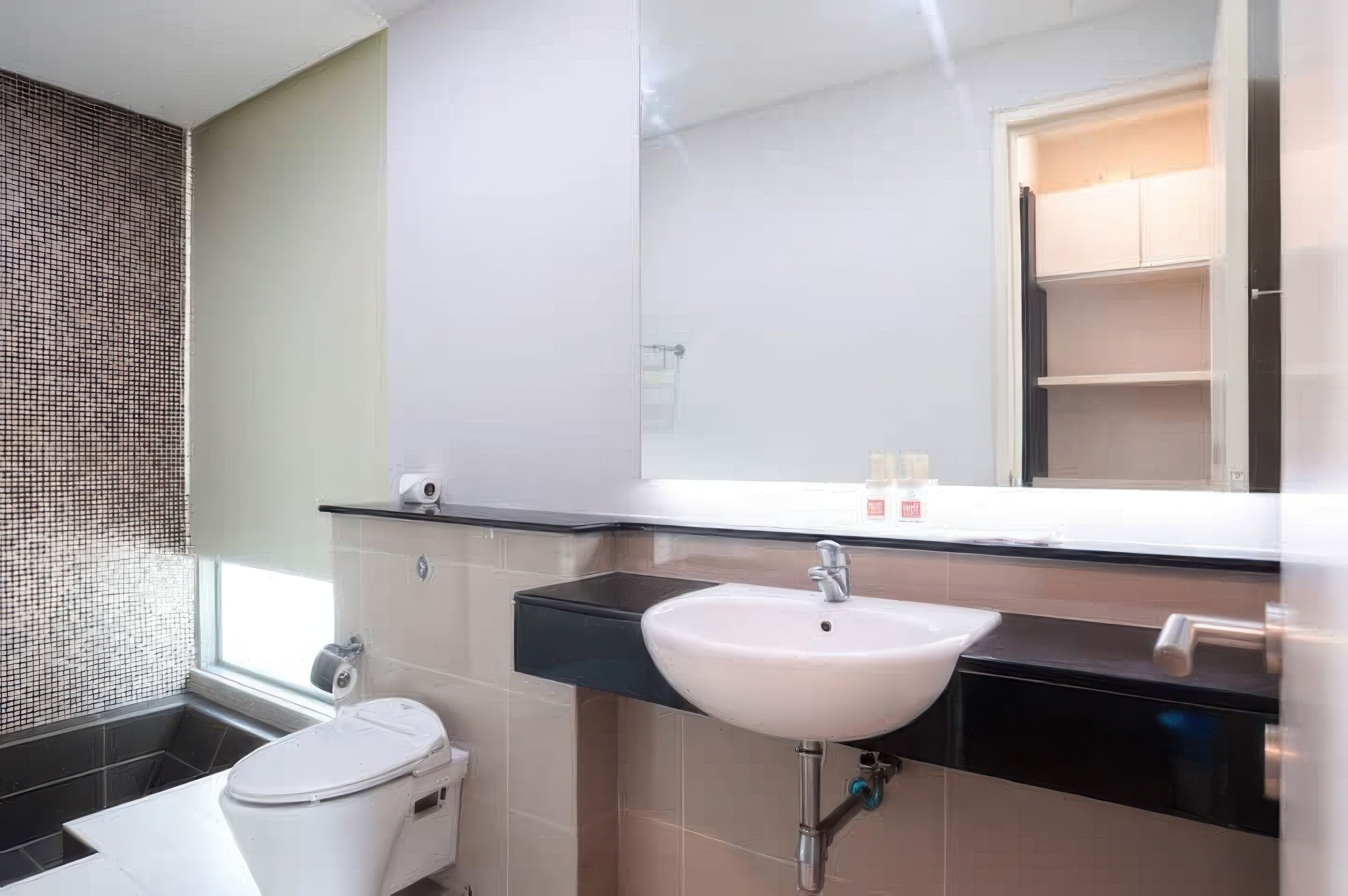 A modern bathroom with a white sink, black countertop, and a large mirror.