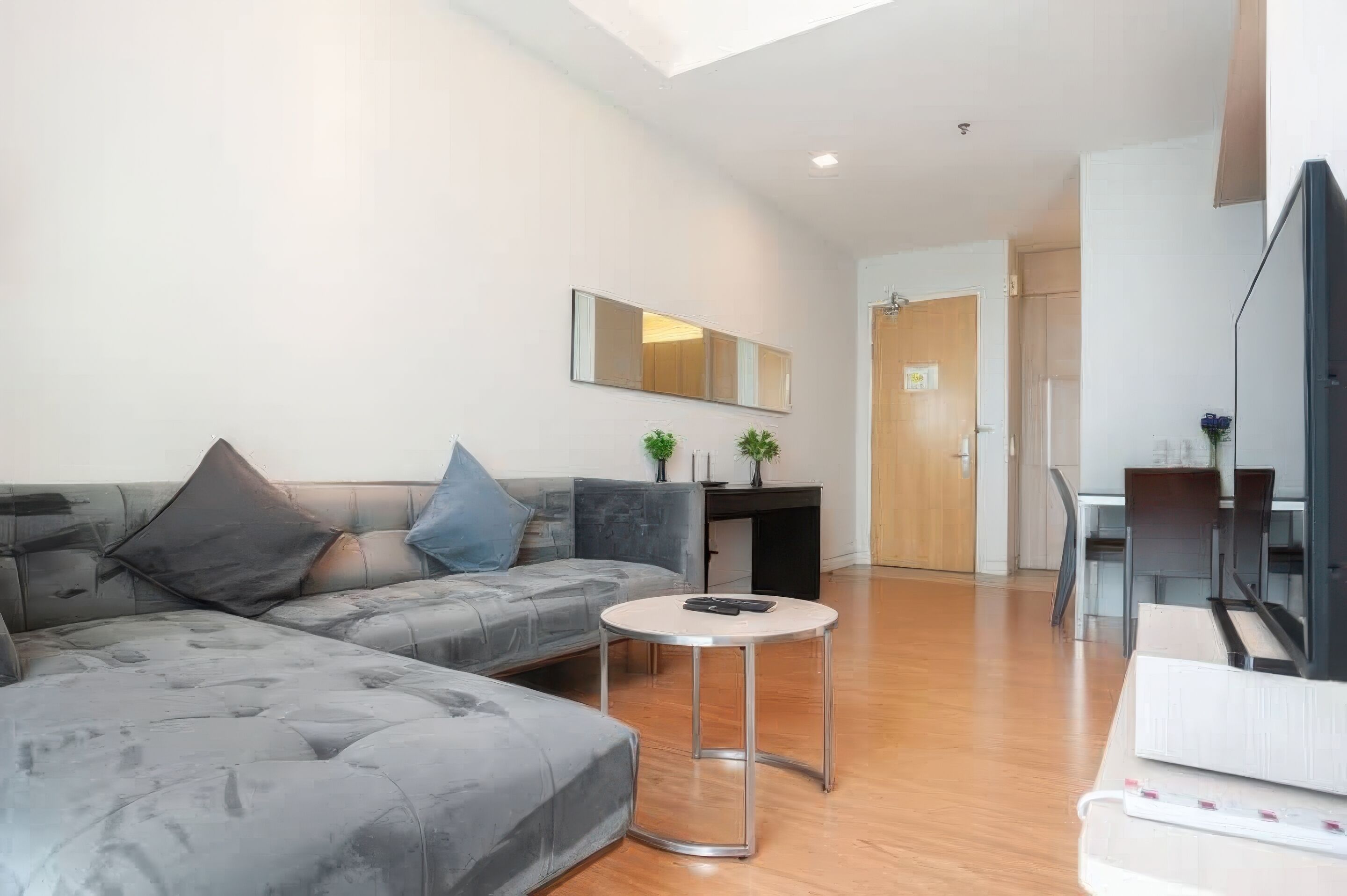 A modern living room with a grey sectional sofa, a round coffee table, and a flat-screen TV.