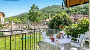 Un balcó amb taula preparat per esmorzar, amb vista a un poble i a les colines.