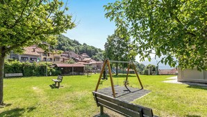 Un parc amb balançs, bancs i un espai de jocs.