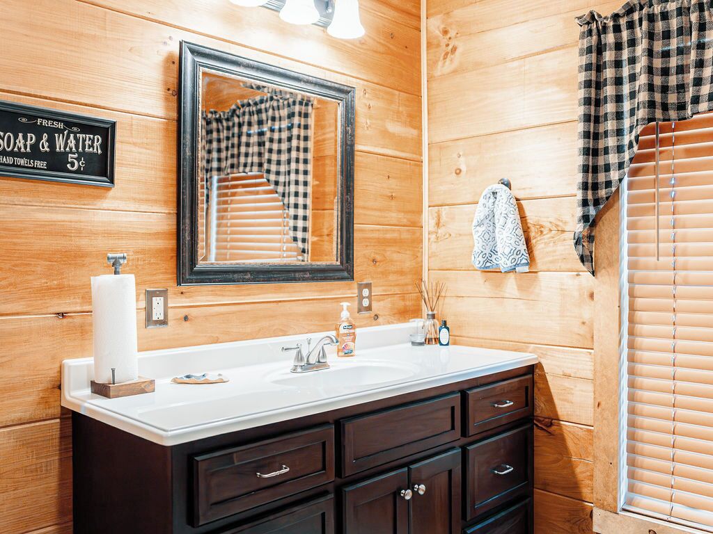 A wooden-paneled bathroom with a sink, mirror, and towel rack.