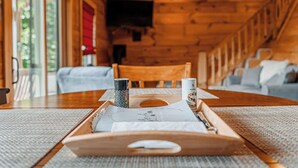 A wooden interior with a dining table, chairs, and a ceiling fan. - Long Valley Lights Cabin - Amazing View & 2 min. to the Blue Ridge Parkway (Fancy Gap)