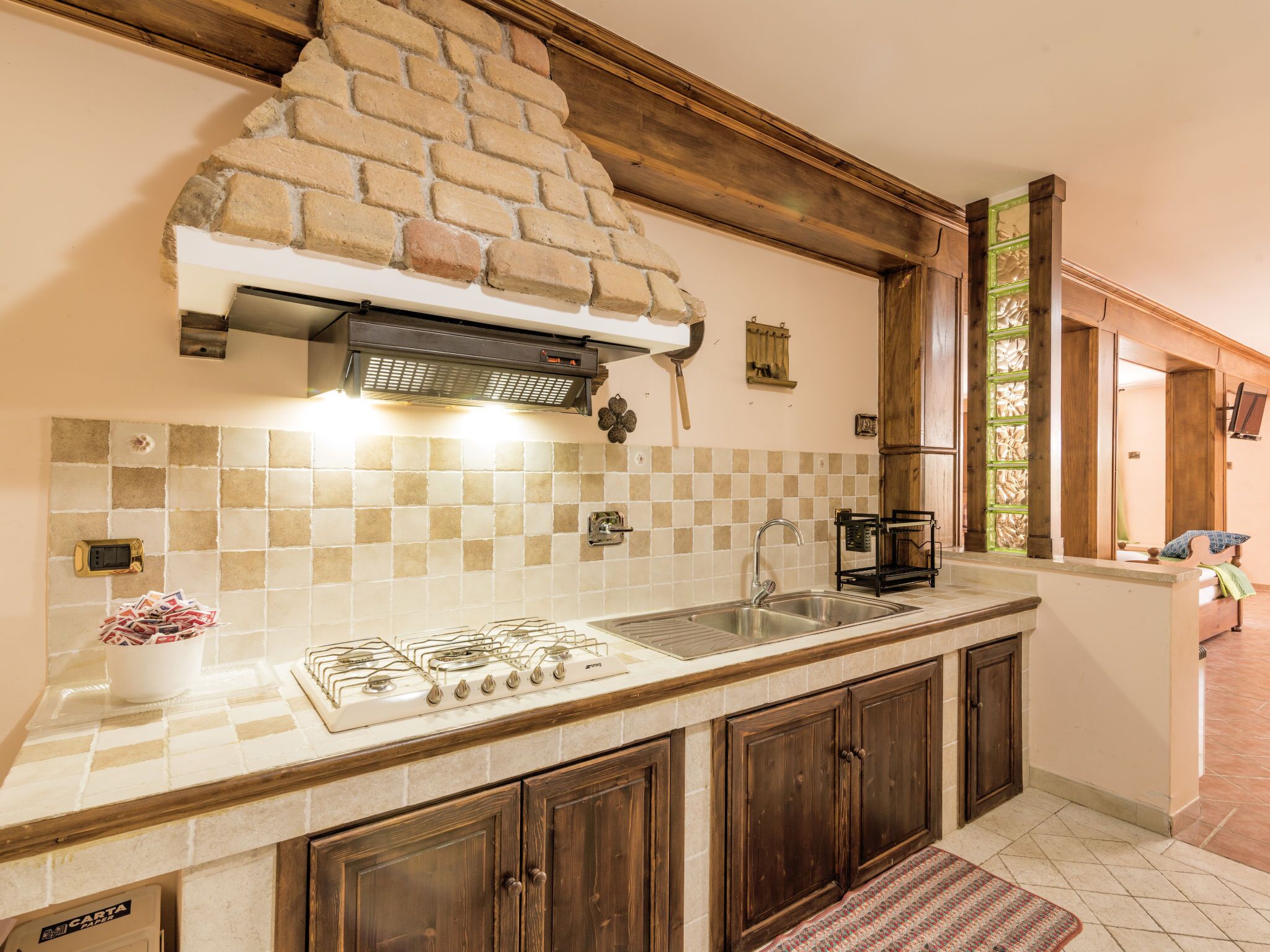 A kitchen with a gas stove, a sink, and wooden cabinets.