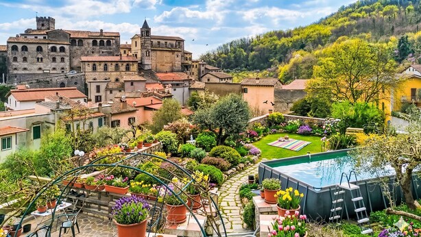 A courtyard with a swimming pool, potted plants, and a view of historic buildings. - Dimora Lucretili by Interhome (Tivoli)