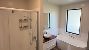 Ein modernes Badezimmer mit einer gläsernen Duschkabine, einer freistehenden Badewanne und einem Waschtisch mit großem Spiegel.