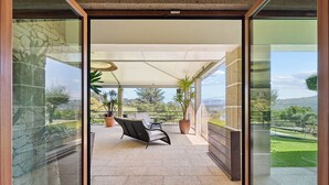 A covered outdoor seating area with a sofa and two potted plants, overlooking a scenic landscape. - GuestReady - Relaxing experience in Queijada (Porto)