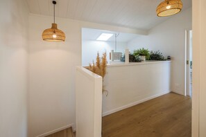 A hallway with white walls, wooden flooring, and two woven pendant lights. - Waterfront Sanctuary, Oneroa - Now open for Christmas and New Year booking! (Waiheke Island)