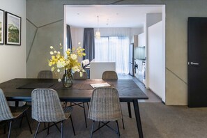 Un espace repas moderne avec une table en bois foncé, quatre chaises en osier et un vase rempli de fleurs.