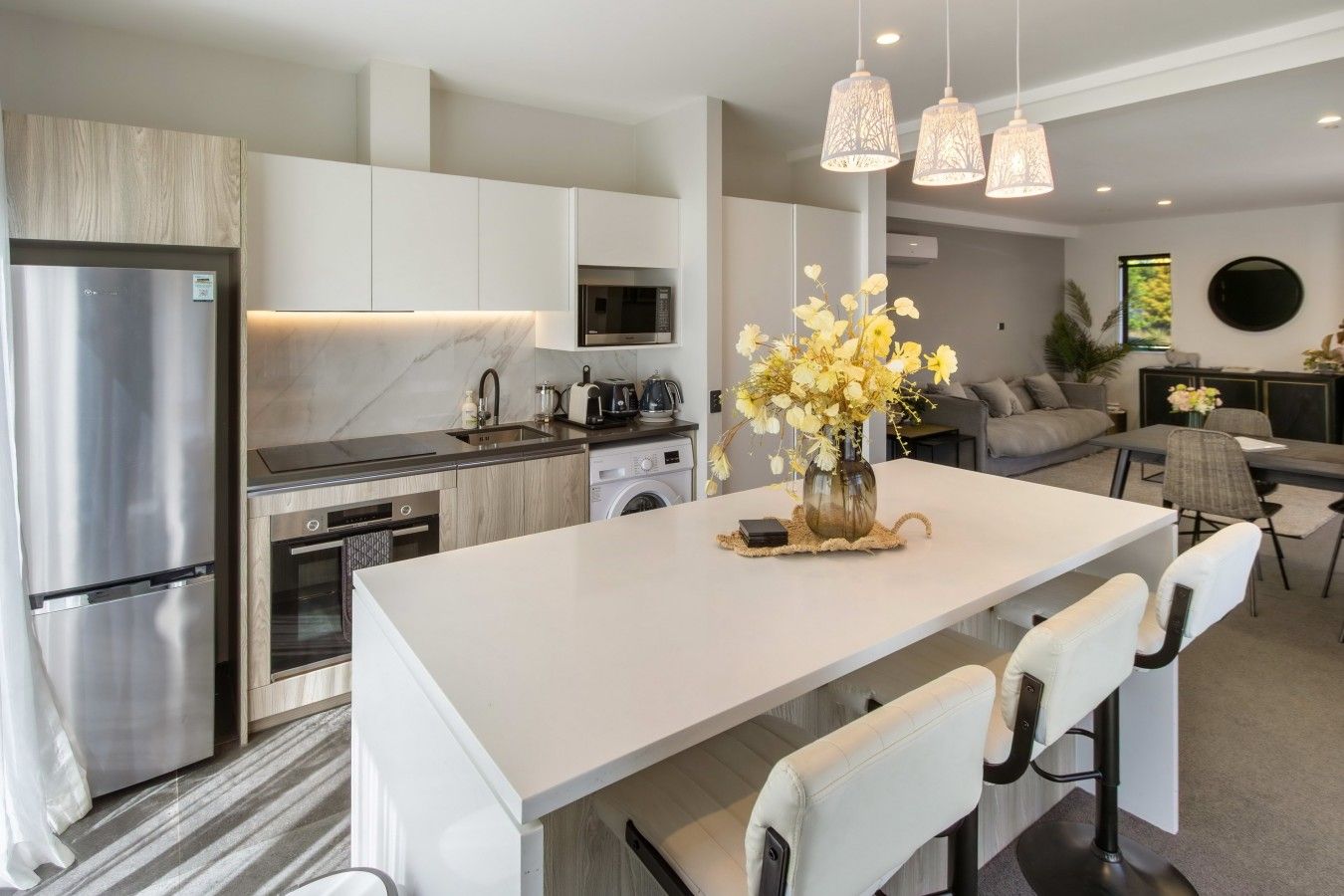 A modern kitchen with stainless steel appliances, a central island with bar stools, and pendant lighting.