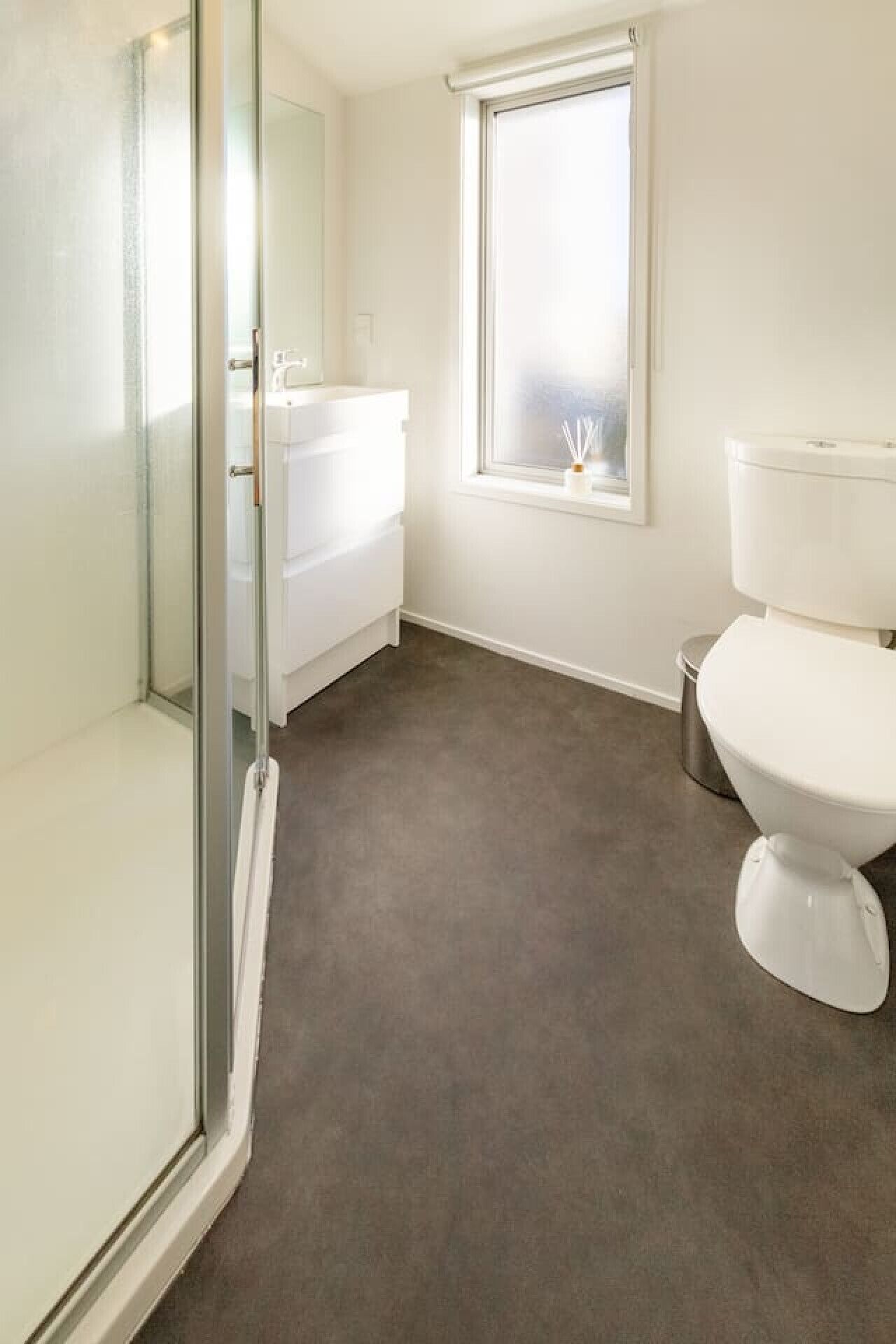 Une salle de bain avec une douche à parois de verre, des toilettes blanches et une fenêtre avec vue.