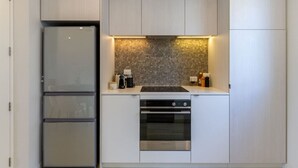 A compact kitchen with a built-in oven, a stovetop, and a refrigerator. - Luxe Central City 2 bedrooms with Carpark (Christchurch)