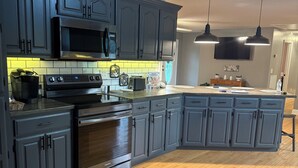 A modern kitchen with grey cabinets, a stainless steel stove, and a microwave. - Charming 3-bedroom house with WiFi and AC in beautiful Loretto (Loretto)