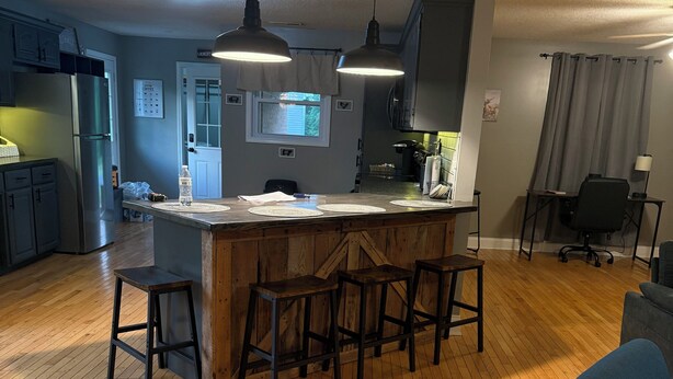 A spacious kitchen with a central island, wooden bar stools, and pendant lighting. - Charming 3-bedroom house with WiFi and AC in beautiful Loretto (Loretto)