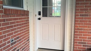 A white front door with a glass panel, a brick wall, and a concrete step leading to the entrance. - Charming 3-bedroom house with WiFi and AC in beautiful Loretto (Loretto)