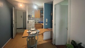 Un comedor con una mesa preparada para cuatro personas, un microondas y un refrigerador al fondo.