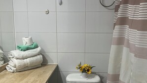 Un baño con inodoro, lavamanos y un pequeño taburete.