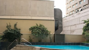 Una piscina con escalones de acceso, rodeada por un muro bajo y vegetación.