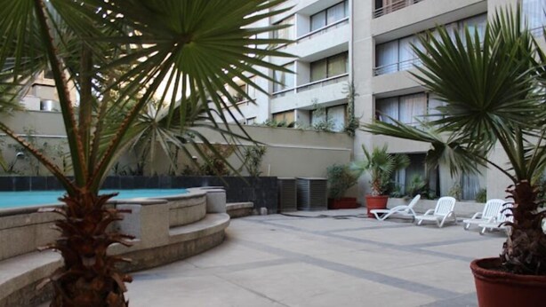 Un patio con piscina, palmeras y sillas de descanso.