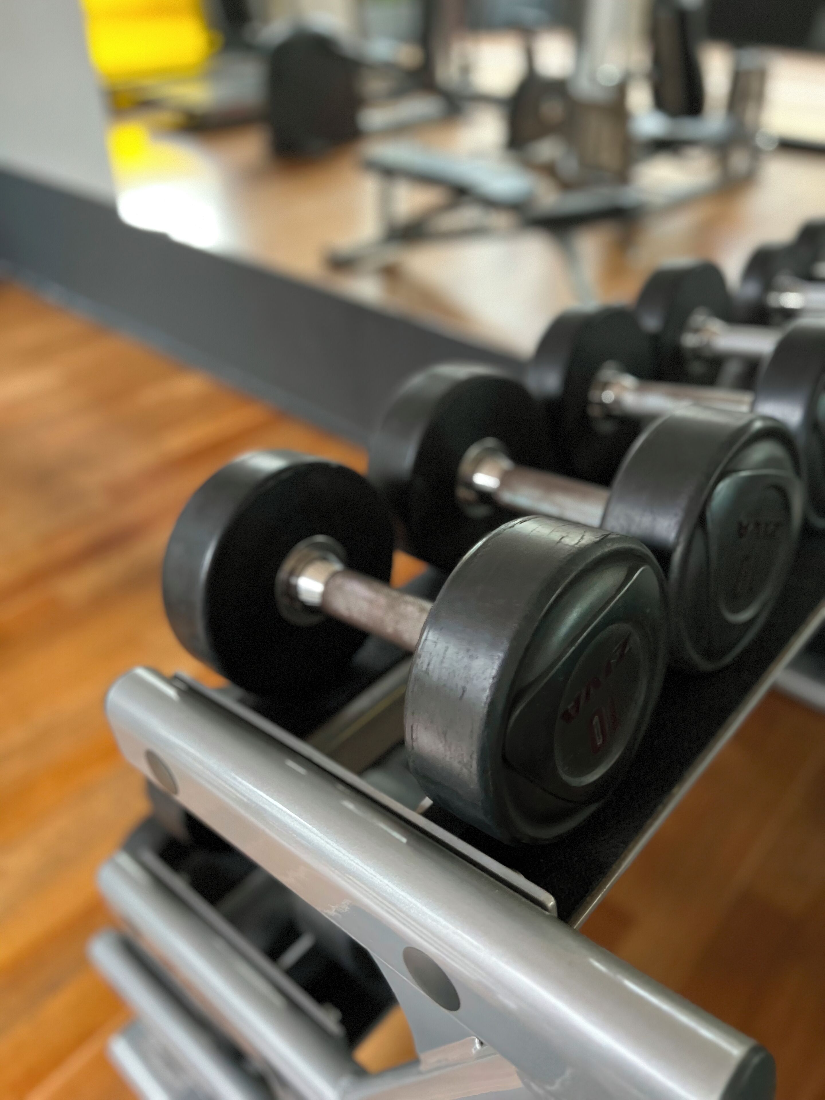 A rack of dumbbells in a gym setting.