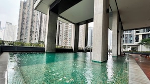 Una piscina en la azotea con agua cristalina, rodeada de edificios altos.