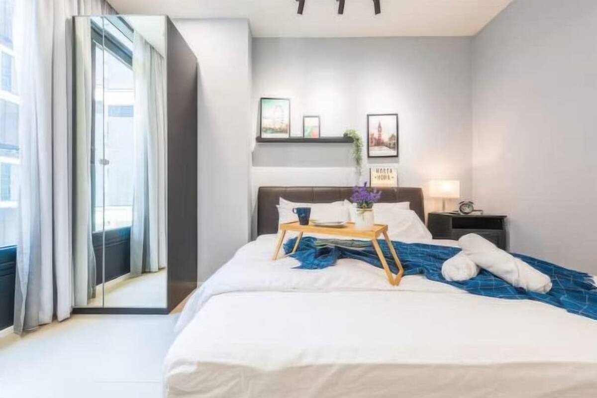 A hotel room with a bed, bedside table, lamp, and a view through a glass door.