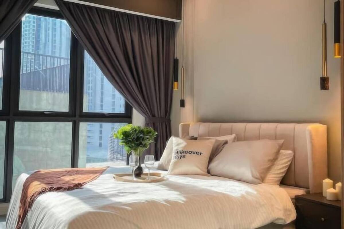 A modern bedroom with a large window, a bed with a headboard, bedside tables, and a small plant.