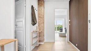 Un pasillo con un banco de madera, un perchero y una pared de ladrillo.