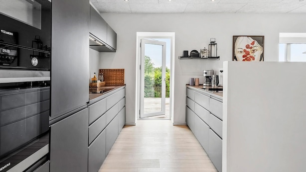 Una cocina moderna con armarios grises, encimera de madera y vistas al exterior.