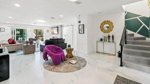 A modern living room with a sofa, a purple chair, a coffee table, and a staircase. - Luxurious 7-bedroom villa with pool/spa and pickleball court in fabulous Naples (Naples)