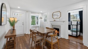 A dining area with a wooden table and chairs, a fireplace, and a view of the outdoors. - Greenville Bungalow Near Downtown + Swamp Rabbit (Greenville)