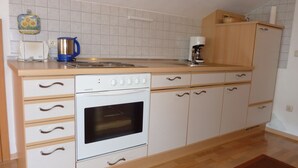 Een compacte keuken met witte kasten, een inbouwoven en een koffiezetapparaat.
