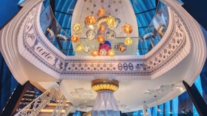 Ein kreisförmiger Innenhof mit Glasdach, dekorativer Beleuchtung und einer zentralen Säule.