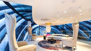 Ein luxuriöser Lounge-Bereich mit hohen Decken und modernem Design, ausgestattet mit stilvoller Sitzgelegenheiten und einem zentralen Couchtisch.