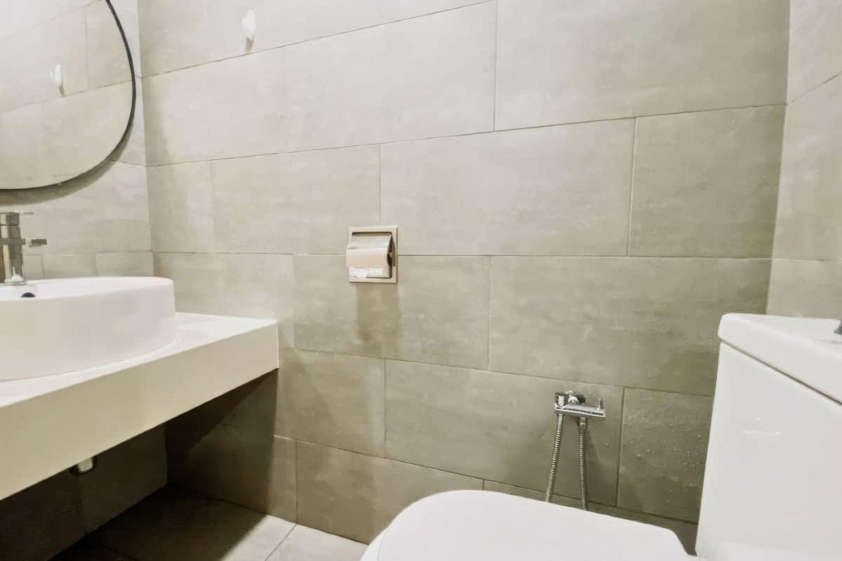 A bathroom with a white sink, a mirror, a toilet, and a shower.