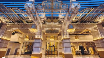 A grand hotel entrance with ornate architectural details, large chandeliers, and a spacious lobby area.