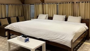 A spacious bedroom with a large bed, a bedside table, and a ceiling fan. - Attanaya Malioboro Suites (Yogyakarta)