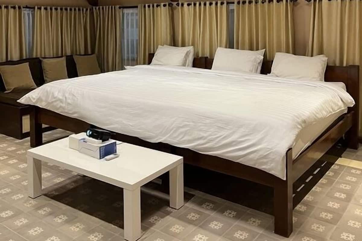 Ein geräumiges Schlafzimmer mit einem großen Bett, einem Nachttisch und einem Deckenventilator.