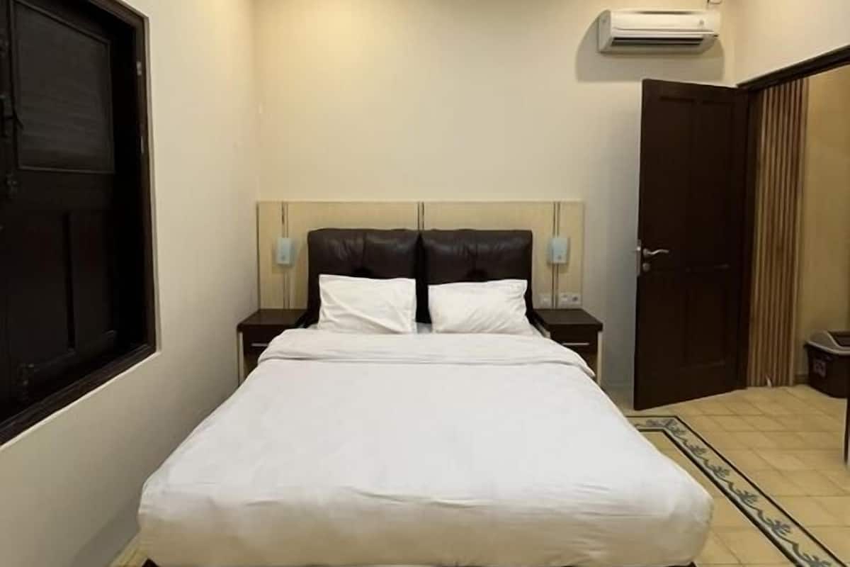 Ein Schlafzimmer mit einem großen Bett, einem Fenster, einer Klimaanlage und einer Tür.