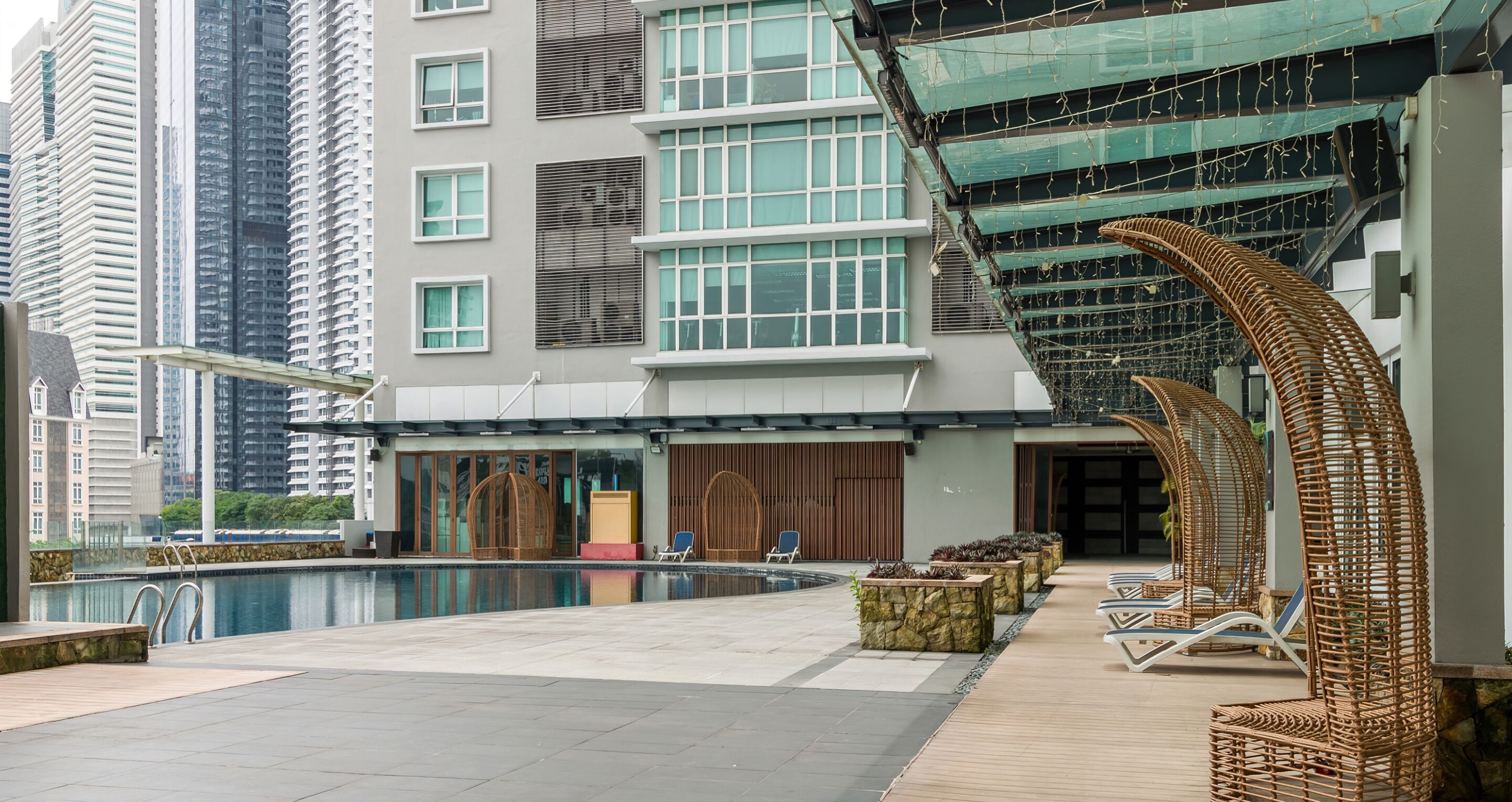 Un hotel moderno con piscina en la azotea, sillones de descanso y vistas a edificios altos circundantes.