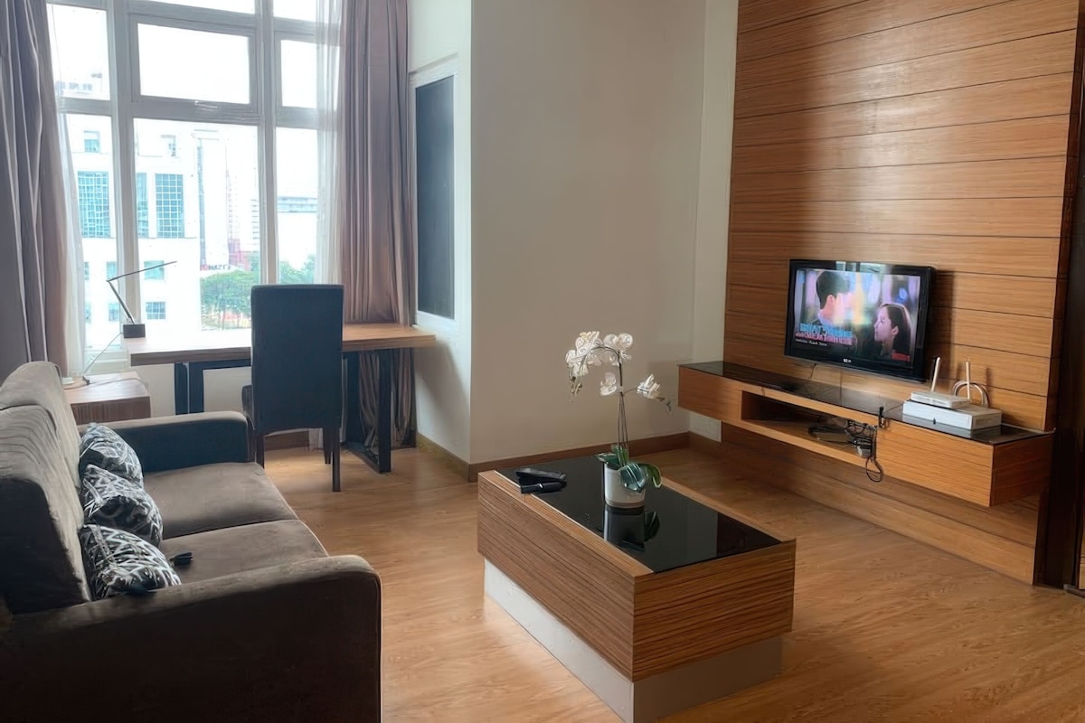 A modern living room with a sofa, a coffee table, a TV, and a desk with a chair.