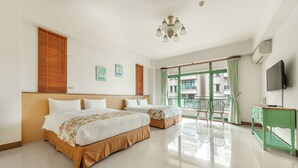Une chambre d’hôtel avec deux lits, une télévision, un balcon donnant sur des immeubles et un bureau vert.